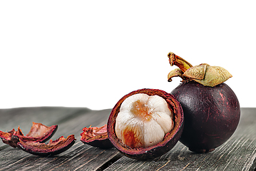 Image showing Whole and opened mangosteen with shells on table