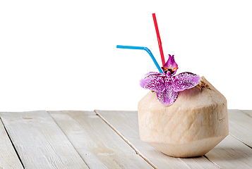 Image showing Young coconut with orchid flower on wooden table