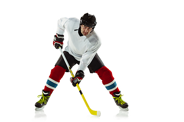 Image showing Young male hockey player with the stick on ice court and white background