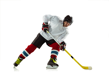 Image showing Young male hockey player with the stick on ice court and white background