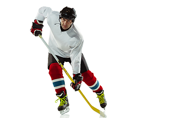 Image showing Young male hockey player with the stick on ice court and white background