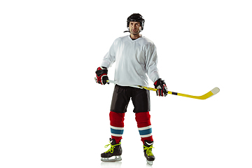 Image showing Young male hockey player with the stick on ice court and white background