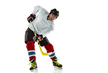 Image showing Young male hockey player with the stick on ice court and white background