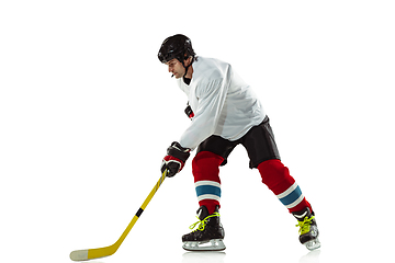 Image showing Young male hockey player with the stick on ice court and white background