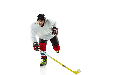 Image showing Young male hockey player with the stick on ice court and white background