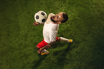 Image showing Top view of caucasian football or soccer player on green background of grass