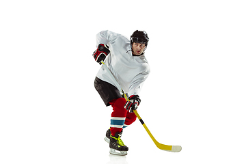 Image showing Young male hockey player with the stick on ice court and white background