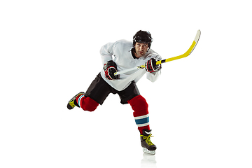 Image showing Young male hockey player with the stick on ice court and white background