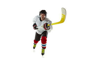 Image showing Young male hockey player with the stick on ice court and white background