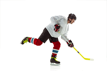 Image showing Young male hockey player with the stick on ice court and white background