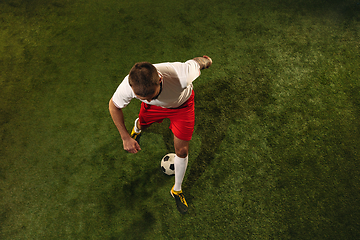 Image showing Top view of caucasian football or soccer player on green background of grass