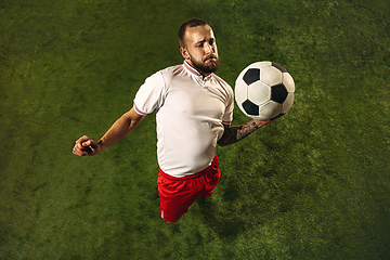 Image showing Top view of caucasian football or soccer player on green background of grass