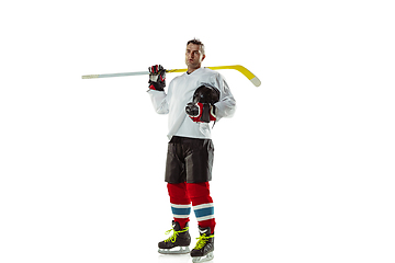 Image showing Young male hockey player with the stick on ice court and white background