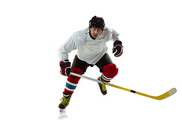 Image showing Young male hockey player with the stick on ice court and white background