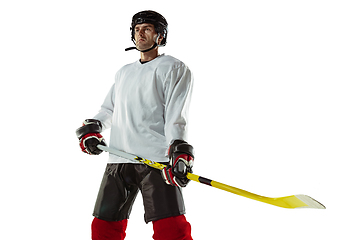 Image showing Young male hockey player with the stick on ice court and white background