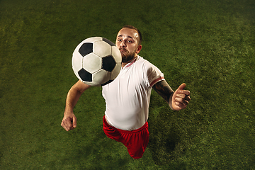 Image showing Top view of caucasian football or soccer player on green background of grass