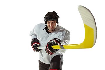 Image showing Young male hockey player with the stick on ice court and white background