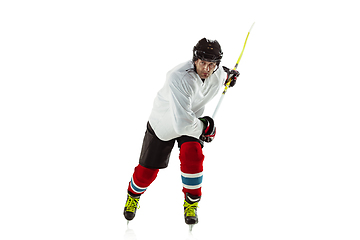 Image showing Young male hockey player with the stick on ice court and white background