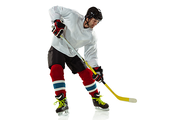 Image showing Young male hockey player with the stick on ice court and white background