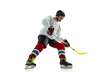 Image showing Young male hockey player with the stick on ice court and white background