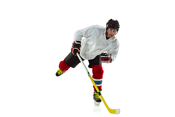 Image showing Young male hockey player with the stick on ice court and white background