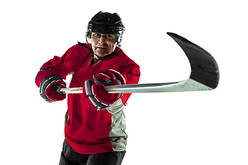 Image showing Male hockey player with the stick on ice court and white background