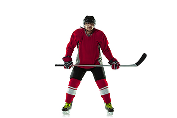 Image showing Male hockey player with the stick on ice court and white background