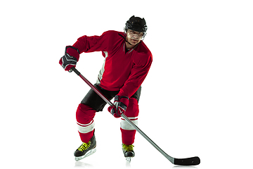 Image showing Male hockey player with the stick on ice court and white background