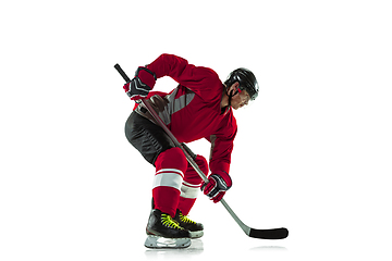 Image showing Male hockey player with the stick on ice court and white background