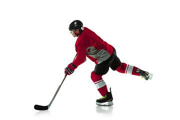 Image showing Male hockey player with the stick on ice court and white background