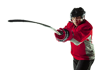 Image showing Male hockey player with the stick on ice court and white background