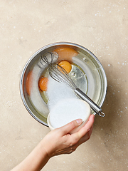 Image showing sugar is added to the eggs in a metal bowl