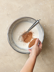 Image showing cocoa powder is added to the whipped eggs and sugar in a metal b