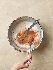 Image showing cocoa powder is added to the whipped eggs and sugar in a metal b