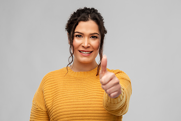 Image showing happy smiling young woman showing thumbs up