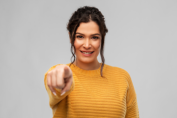 Image showing smiling young woman pointing finger to camera