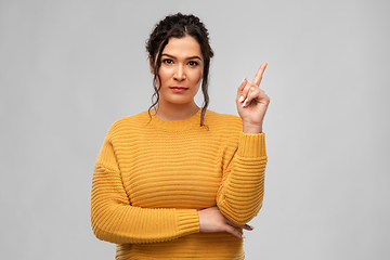 Image showing serious young woman pointing finger up