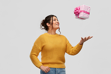 Image showing smiling young woman throwing gift box