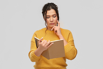 Image showing pensive young woman reading diary or notebook