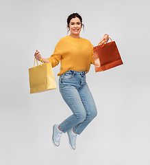 Image showing happy young woman jumping with shopping bags