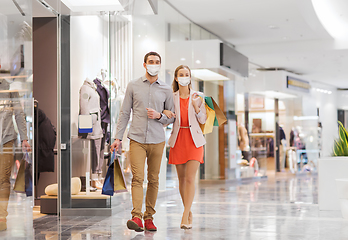 Image showing couple in medical masks with shopping bags in mall