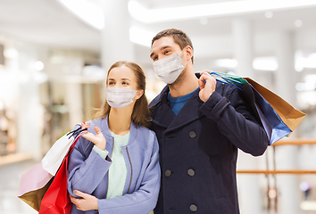 Image showing couple in medical masks with shopping bags in mall