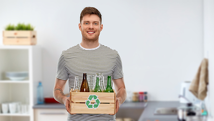 Image showing smiling young man sorting glass waste at home