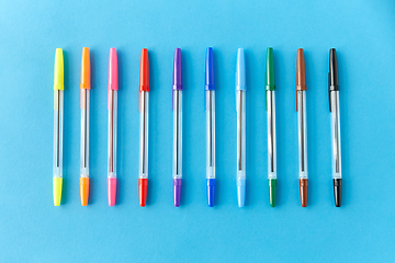 Image showing row of multicolored pens on blue background