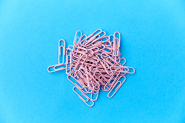 Image showing heap of pink office clips on blue background