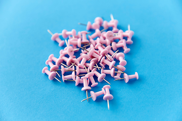 Image showing heap of pink office pins on blue background