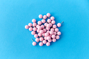 Image showing heap of pink office pins on blue background