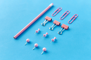 Image showing pink pencil, pins and clips on blue background