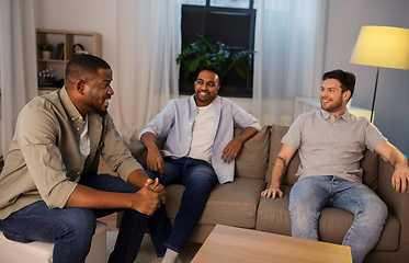 Image showing happy male friends talking at home at night