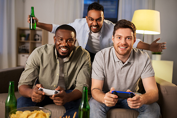 Image showing happy friends playing video games at home at night